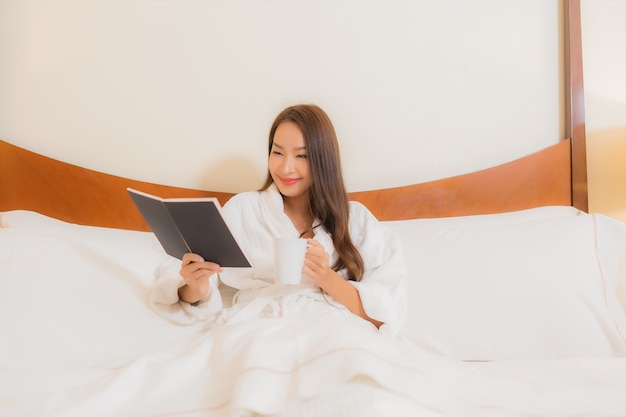 Retrato linda jovem asiática lendo livro na cama, no interior do quarto