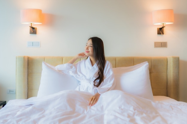 Retrato linda jovem asiática na cama com um celular inteligente