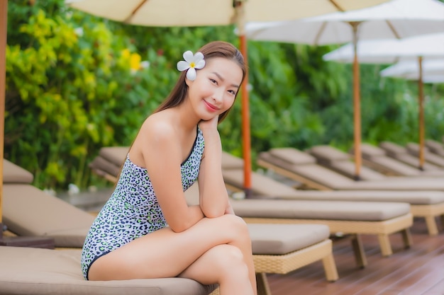 Retrato linda jovem asiática relaxando ao ar livre na piscina em viagem de férias
