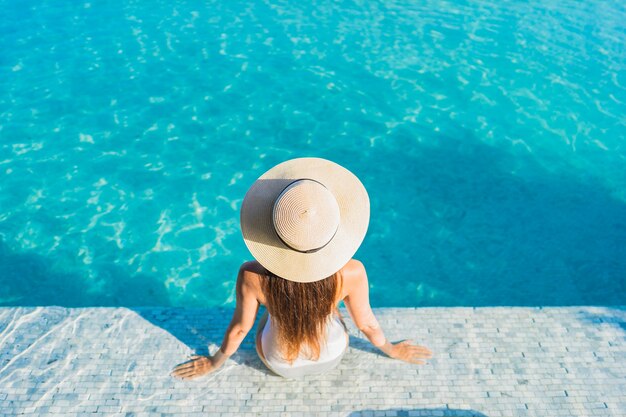 Retrato linda jovem asiática relaxando ao redor da piscina ao ar livre com vista da cidade