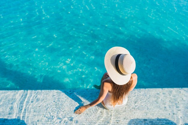 Retrato linda jovem asiática relaxando ao redor da piscina ao ar livre com vista da cidade