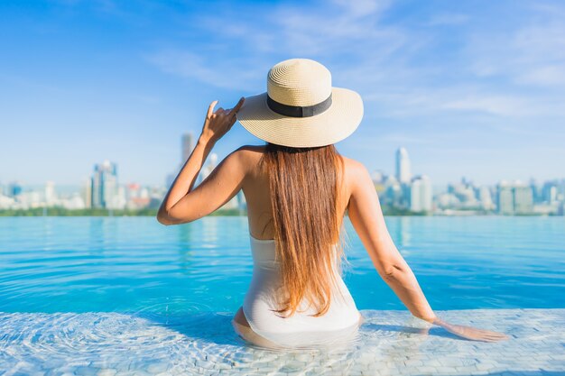 Retrato linda jovem asiática relaxando ao redor da piscina ao ar livre com vista da cidade