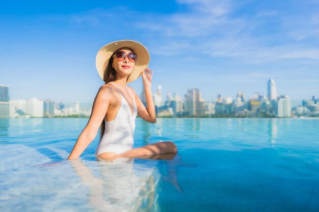 Retrato linda jovem asiática relaxando ao redor da piscina ao ar livre com vista da cidade