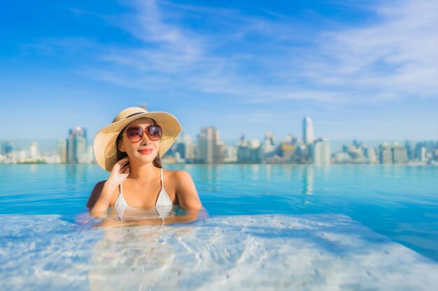 Retrato linda jovem asiática relaxando ao redor da piscina ao ar livre com vista da cidade