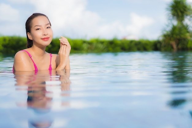 Retrato linda jovem asiática relaxando e aproveitando a piscina ao ar livre nas férias