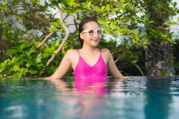 Retrato linda jovem asiática relaxando e aproveitando a piscina ao ar livre nas férias