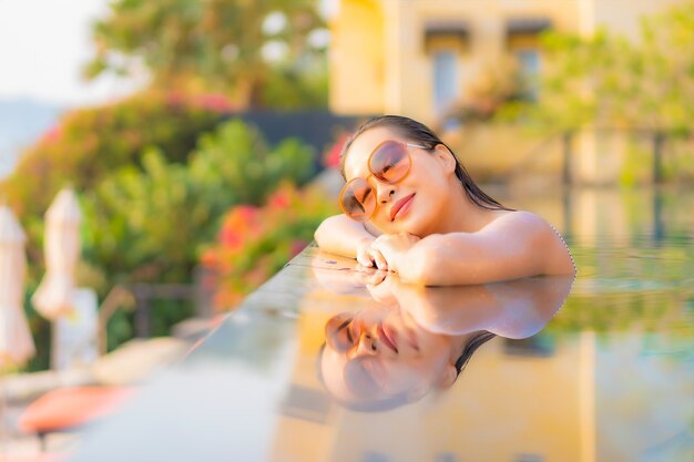 Retrato linda jovem asiática relaxando, sorrindo, aproveitando o lazer ao redor da piscina em um hotel resort nas férias