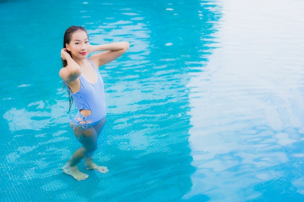 Retrato linda jovem asiática relaxando, sorrindo, relaxando ao redor da piscina ao ar livre