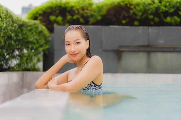 Retrato linda jovem asiática relaxando sorriso ao redor da piscina para lazer e férias