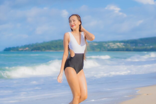 Retrato linda jovem asiática relaxando sorriso ao redor da praia, mar, oceano, nas férias