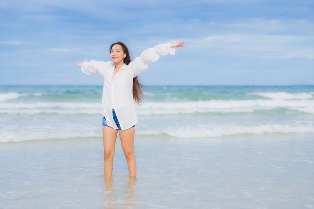 Retrato linda jovem asiática relaxando sorriso ao redor da praia, mar, oceano, numa viagem de férias de férias