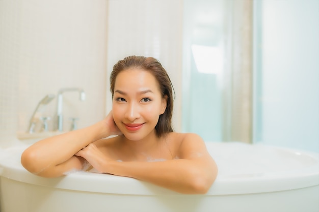 Retrato linda jovem asiática relaxando sorriso na banheira no interior do banheiro