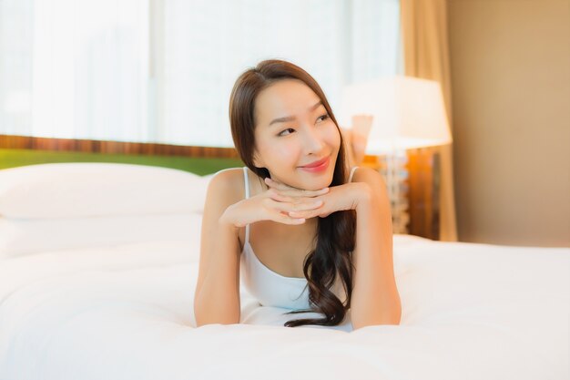 Retrato linda jovem asiática relaxando sorriso na cama, no interior do quarto