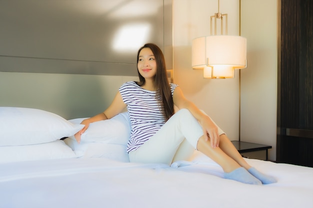 Retrato linda jovem asiática relaxando sorriso na cama, no interior do quarto