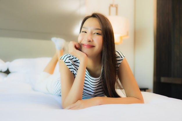 Retrato linda jovem asiática relaxando sorriso na cama, no interior do quarto