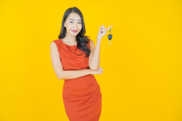 Retrato linda jovem asiática sorrindo com a chave do carro em amarelo