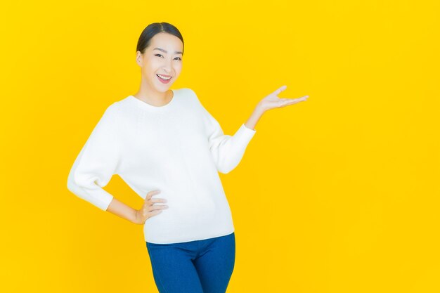 Retrato linda jovem asiática sorrindo com ação em amarelo