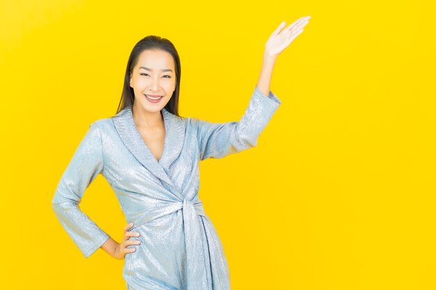 Retrato linda jovem asiática sorrindo com ação na parede amarela