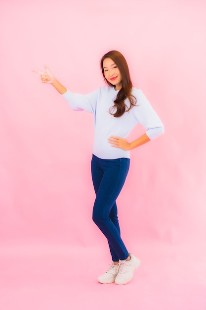 Retrato linda jovem asiática sorrindo com ação na parede rosa isolada