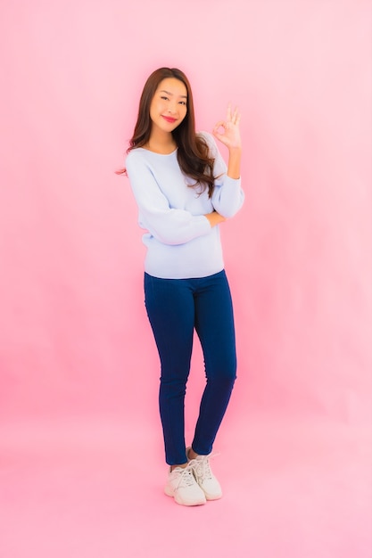 Retrato linda jovem asiática sorrindo com ação na parede rosa isolada