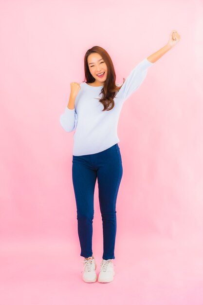 Retrato linda jovem asiática sorrindo com ação na parede rosa isolada