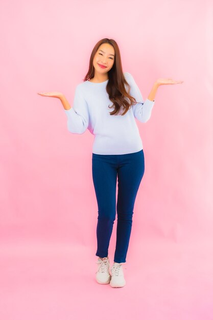 Retrato linda jovem asiática sorrindo com ação na parede rosa isolada