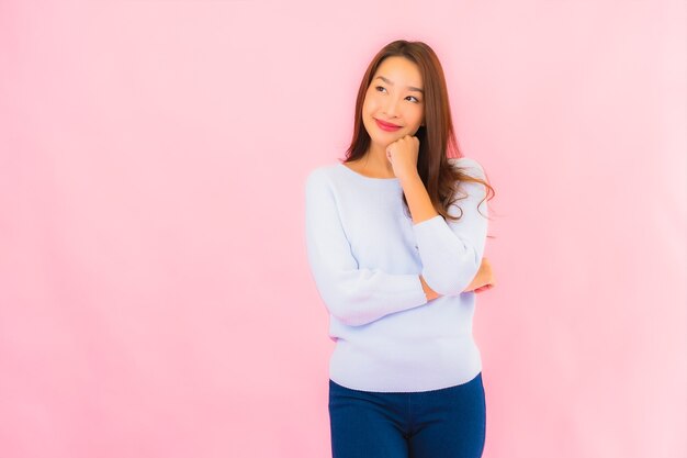 Retrato linda jovem asiática sorrindo com ação na parede rosa isolada