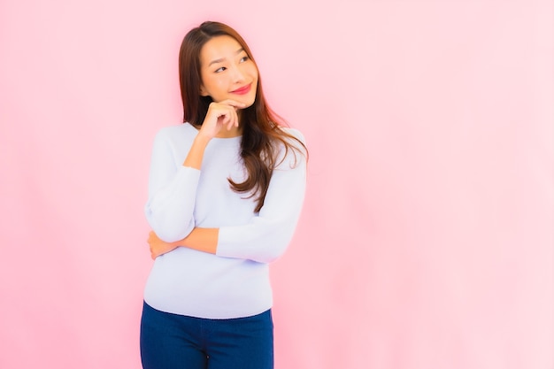 Retrato linda jovem asiática sorrindo com ação na parede rosa isolada