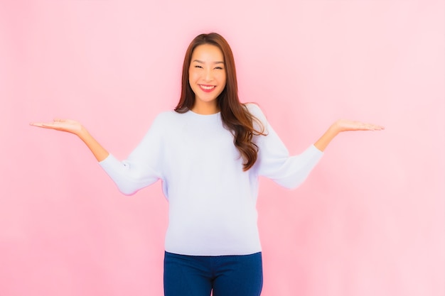 Retrato linda jovem asiática sorrindo com ação na parede rosa isolada