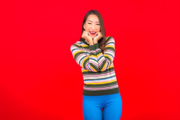 Foto grátis retrato linda jovem asiática sorrindo com ação na parede vermelha isolada