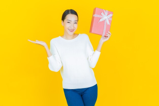 Retrato linda jovem asiática sorrindo com caixa de presente vermelha em amarelo