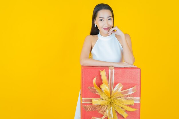 Retrato linda jovem asiática sorrindo com caixa de presente vermelha em amarelo