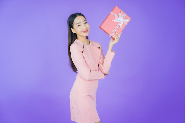 Retrato linda jovem asiática sorrindo com caixa de presente vermelha sobre fundo colorido