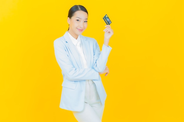 Retrato linda jovem asiática sorrindo com cartão de crédito em amarelo