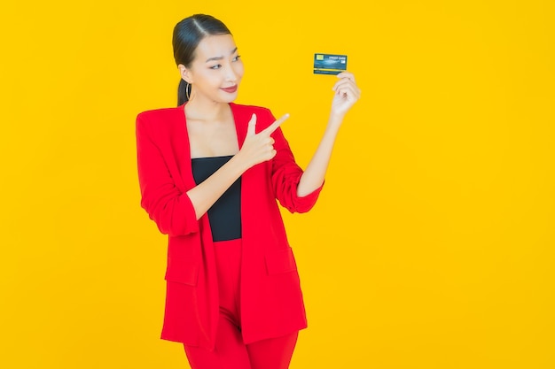 Retrato linda jovem asiática sorrindo com cartão de crédito em amarelo