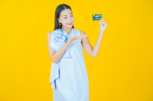 Retrato linda jovem asiática sorrindo com cartão de crédito em amarelo