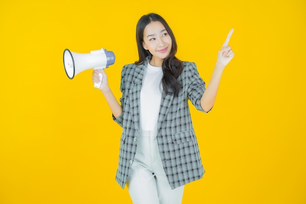 Retrato linda jovem asiática sorrindo com megafone na cor de fundo Foto Premium