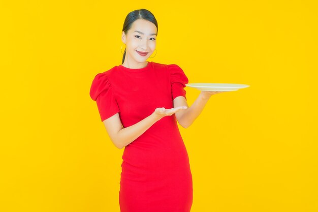 Retrato linda jovem asiática sorrindo com prato vazio em amarelo