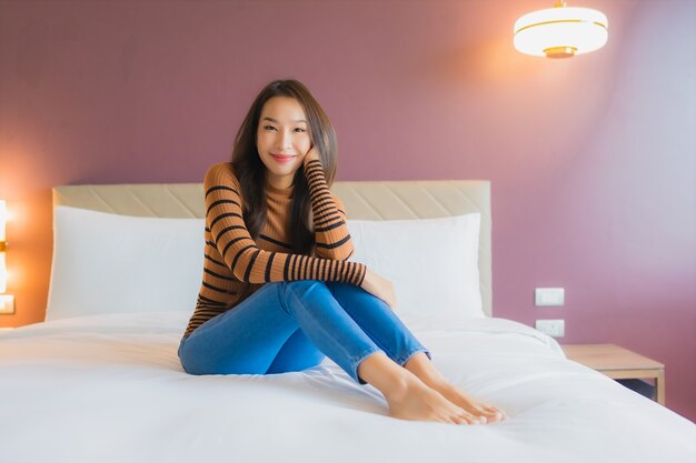 Retrato linda jovem asiática sorrindo relaxando na cama