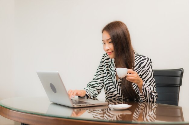 Retrato linda jovem asiática usando laptop na mesa de trabalho na sala