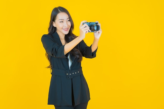 Retrato linda jovem asiática usar câmera em amarelo