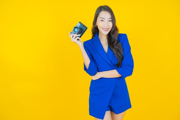 Retrato linda jovem asiática usar câmera em amarelo