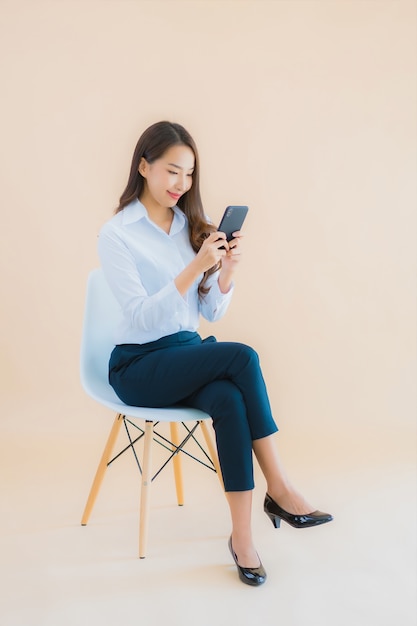 Retrato linda jovem mulher asiática de negócios sentada na cadeira com o smartphone