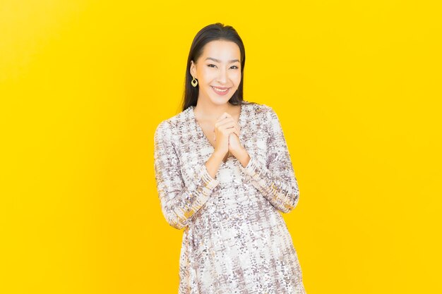 Retrato lindo jovem asiático sorrindo posando em amarelo