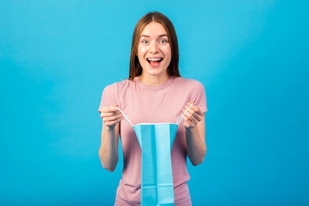 Retrato médio-tiro de uma mulher feliz, segurando uma sacola de compras