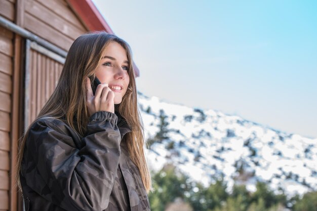 Retrato mulher jovem e bonita no inverno na neve usando telefone celular