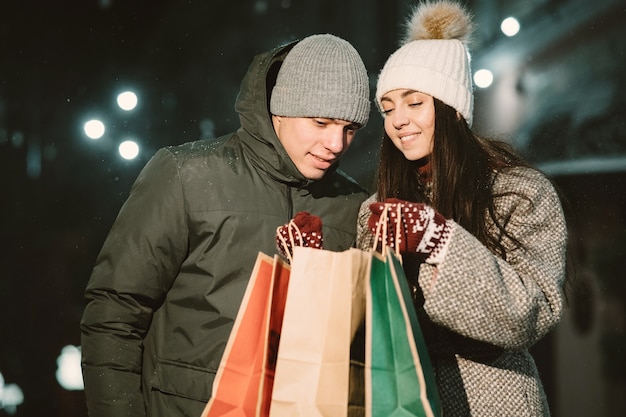 Foto grátis retrato noturno ao ar livre de um jovem casal com sacolas de compras