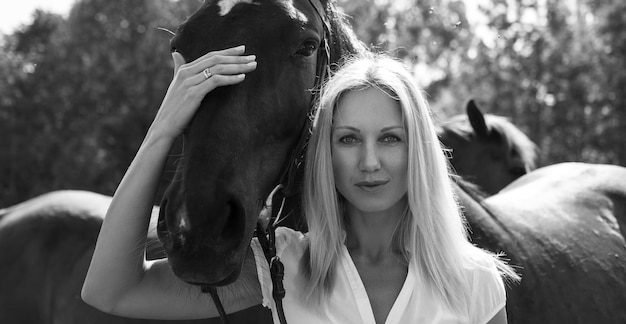 Retrato preto e branco de mulher loira com cavalo.