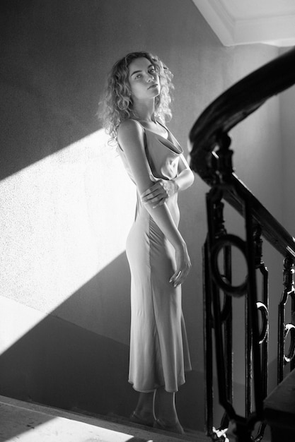 Retrato preto e branco de uma linda mulher posando dentro de casa em um vestido