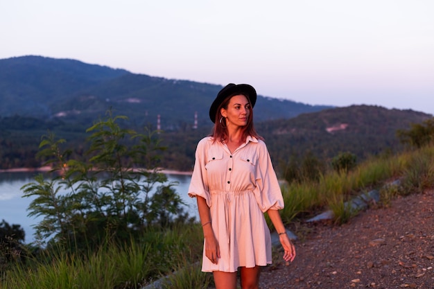 Retrato romântico de jovem caucasiana com vestido de verão relaxando no parque na montanha com vista para o mar tropical